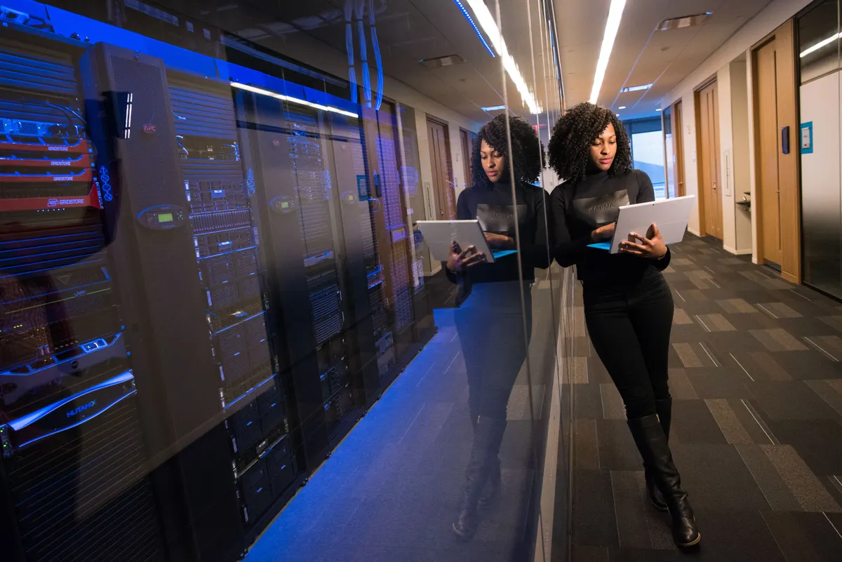 A woman navigating a data center on a laptop, representing the DNS infrastructure behind email authentication