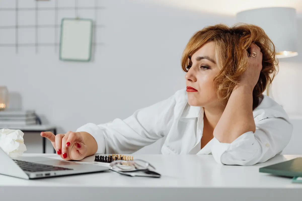 A business owner looking frustrated at her laptop, having outgrown her website builder