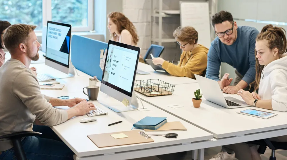 A creative agency team working together on computers in an office