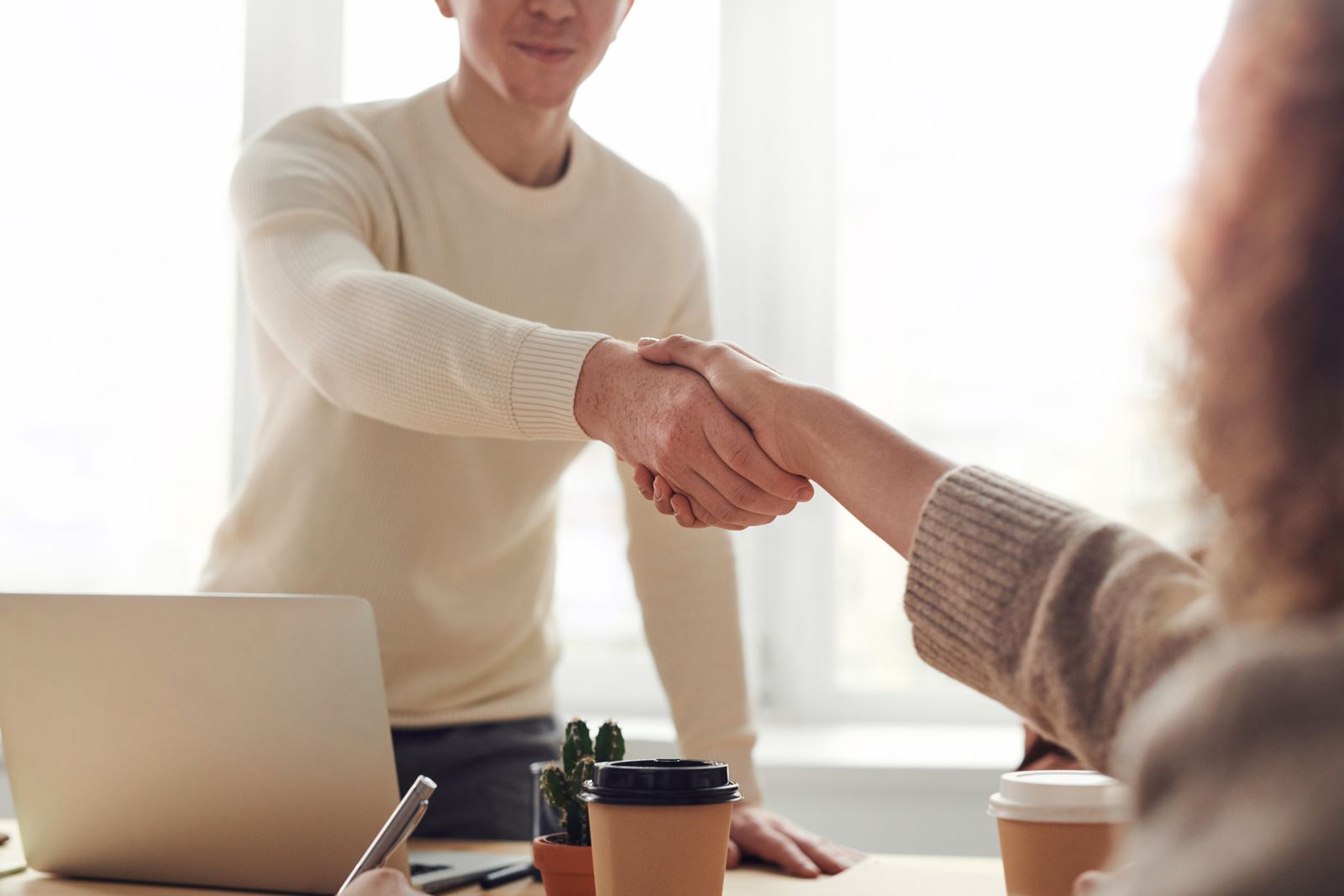 Two business owners discussing project questions with a developer in a bright meeting