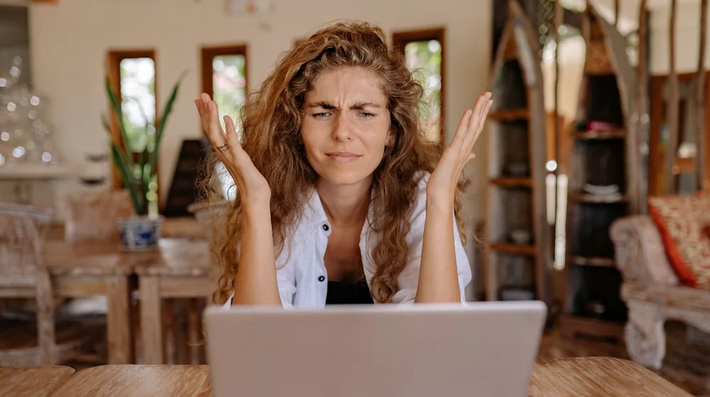 A frustrated woman waiting at her laptop for a slow website to load